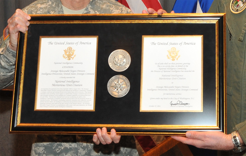 Two military men holding the National Intelligence Meritorious Unit Citation